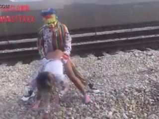 Clown eikels schoolmeisje op trein tracks